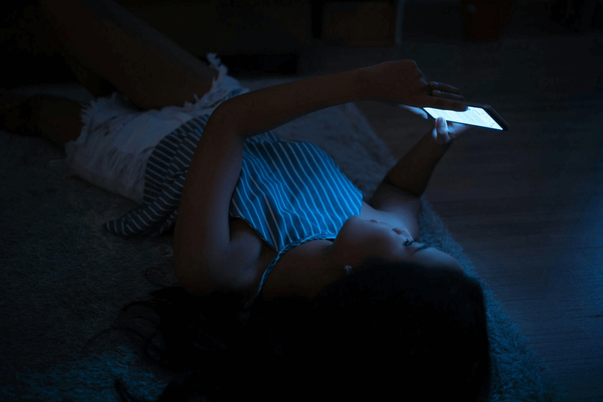Someone laying in bed using a phone in the dark