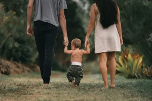 Mother and father walking barefoot in nature with their baby